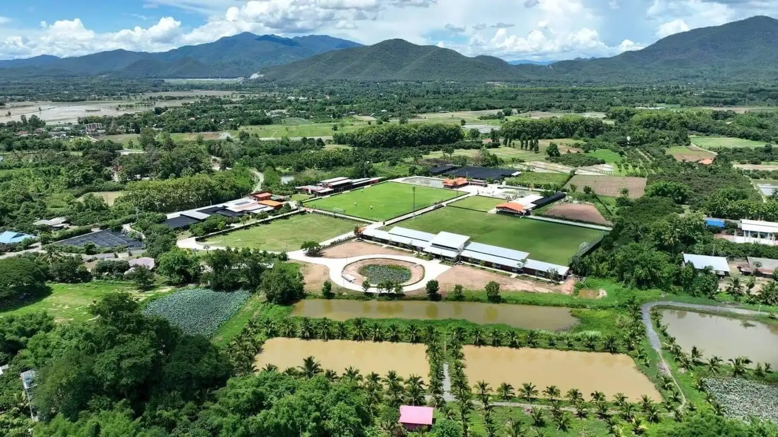 Aerial view of the resort pitches among farmland and forest, with mountains behind