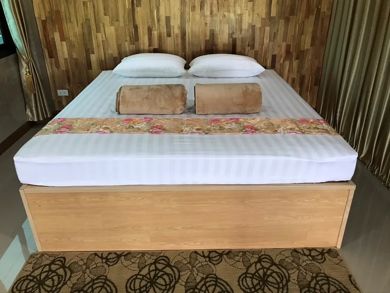 A double bed with a floral runner against a wood-panelled wall