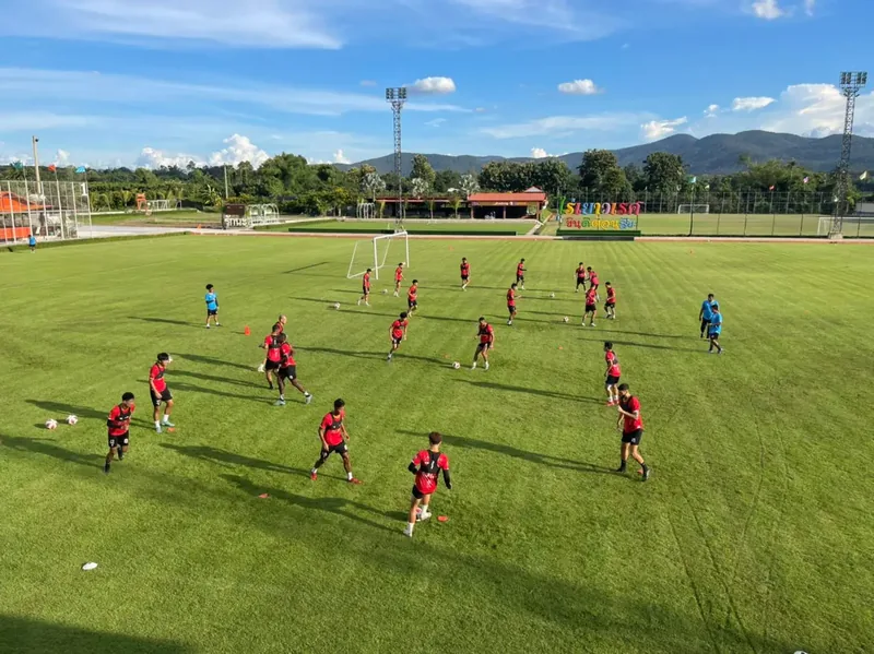 Players running passing drills in pairs across the pitch, hills behind