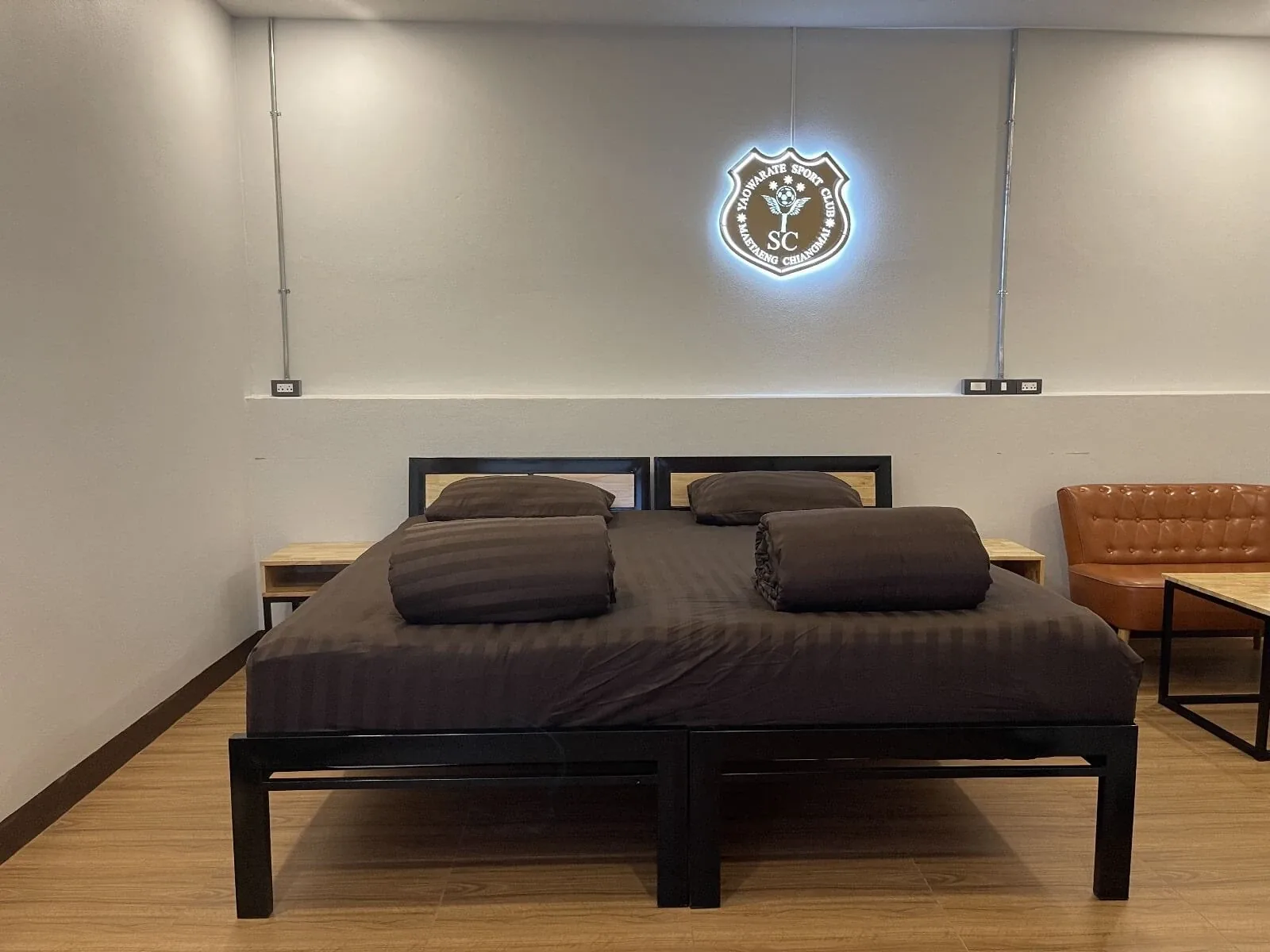 A twin room with two beds and the illuminated club crest on the wall